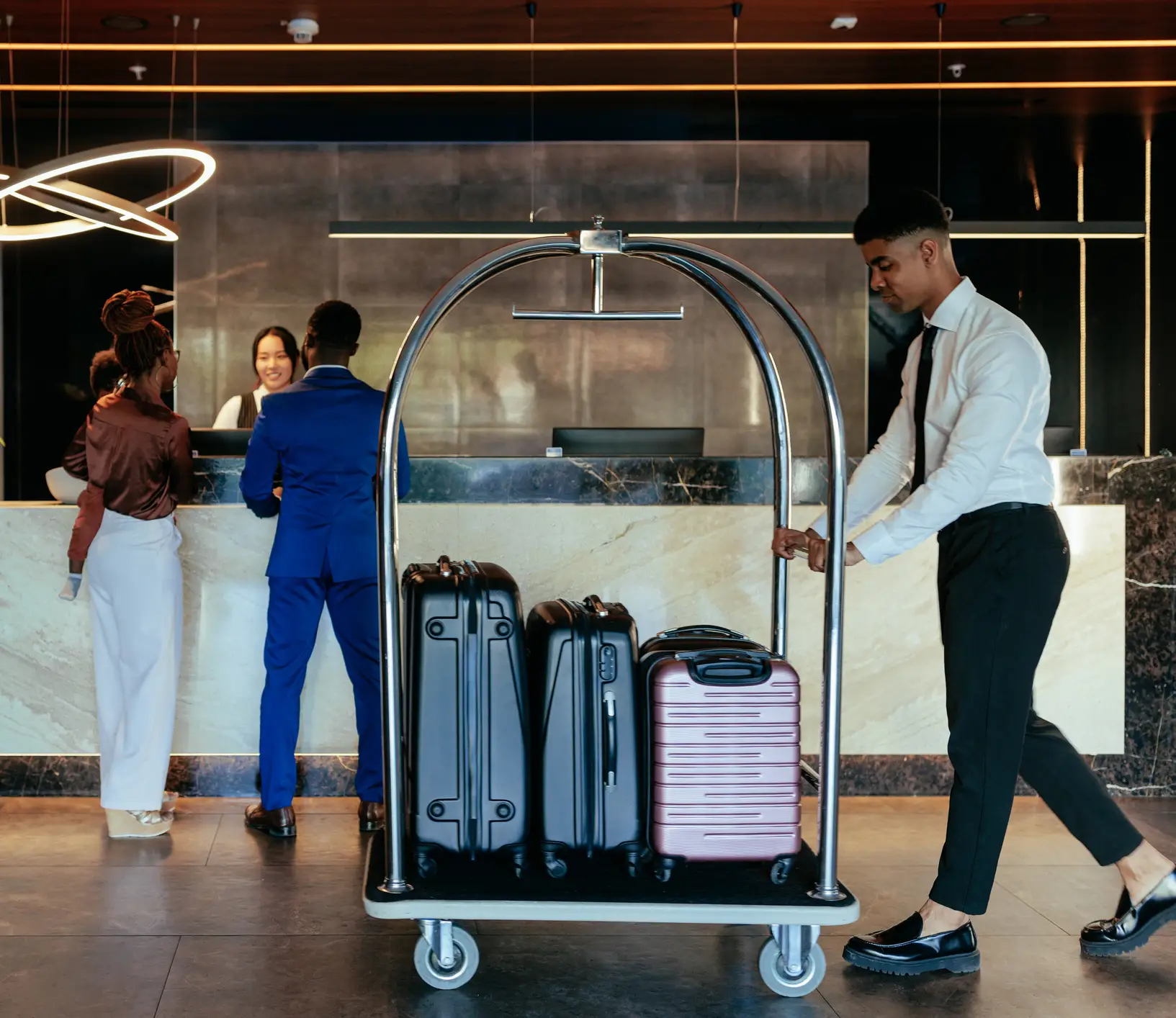 Man pushing a luggage cart in front of a hotel lobby